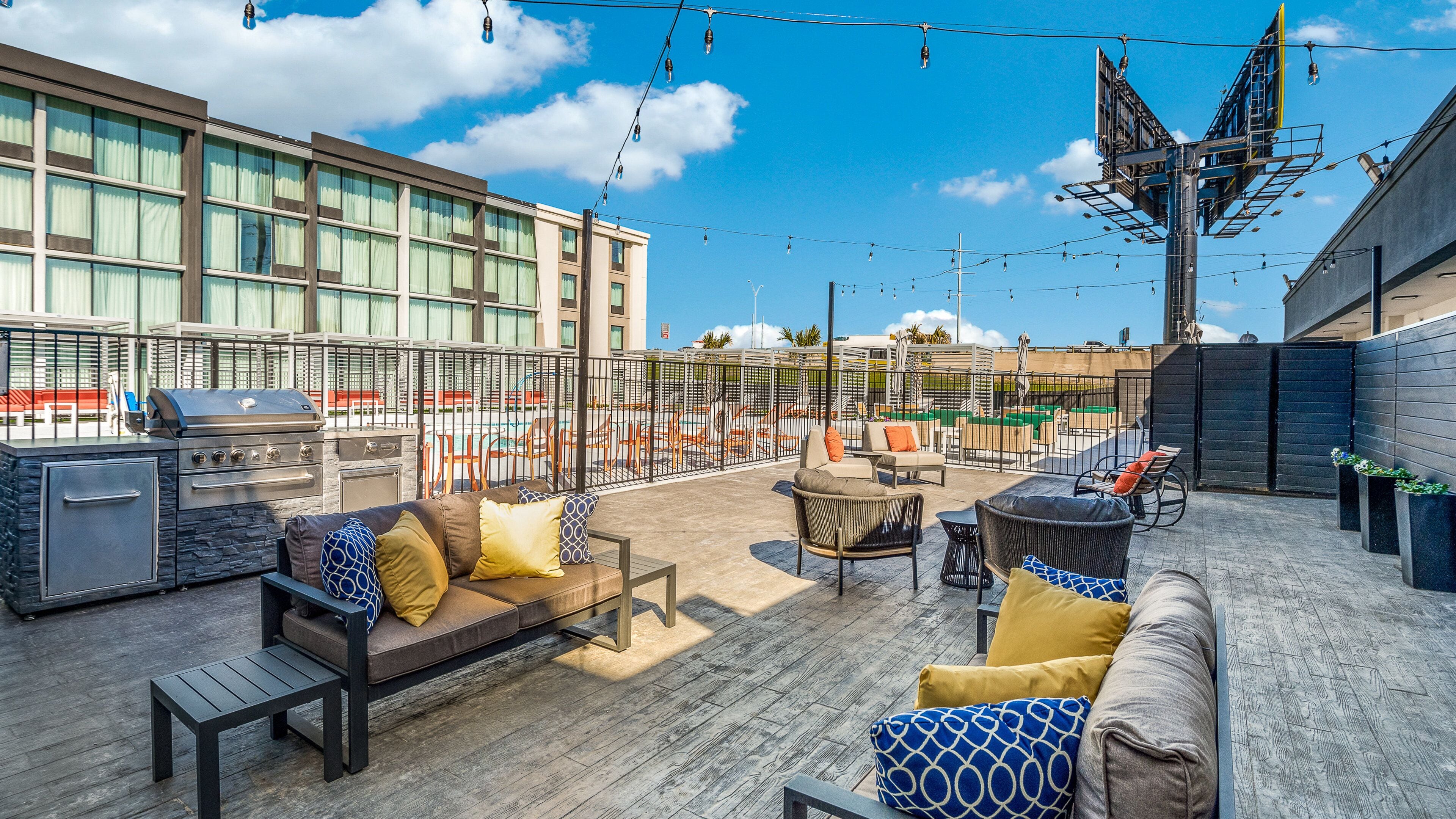 An outdoor patio with a grill, seating area, and a view of a swimming pool.