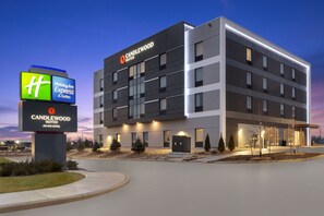 Ein modernes Hotelgebäude mit Holiday Inn Express Schild, Candlewood Suites Schriftzug und einem gut beleuchteten Eingang.