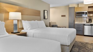 Een hotelkamer met twee bedden, een kitchenette en een kleine badkamer.