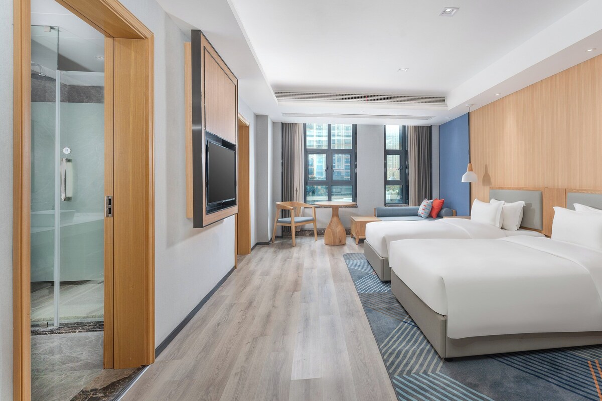 A modern hotel room with a large bed, a desk, and a TV.