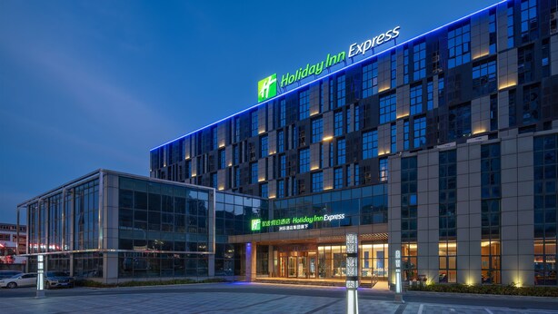 Un hotel Holiday Inn Express con fachada de vidrio moderno y señalización iluminada.