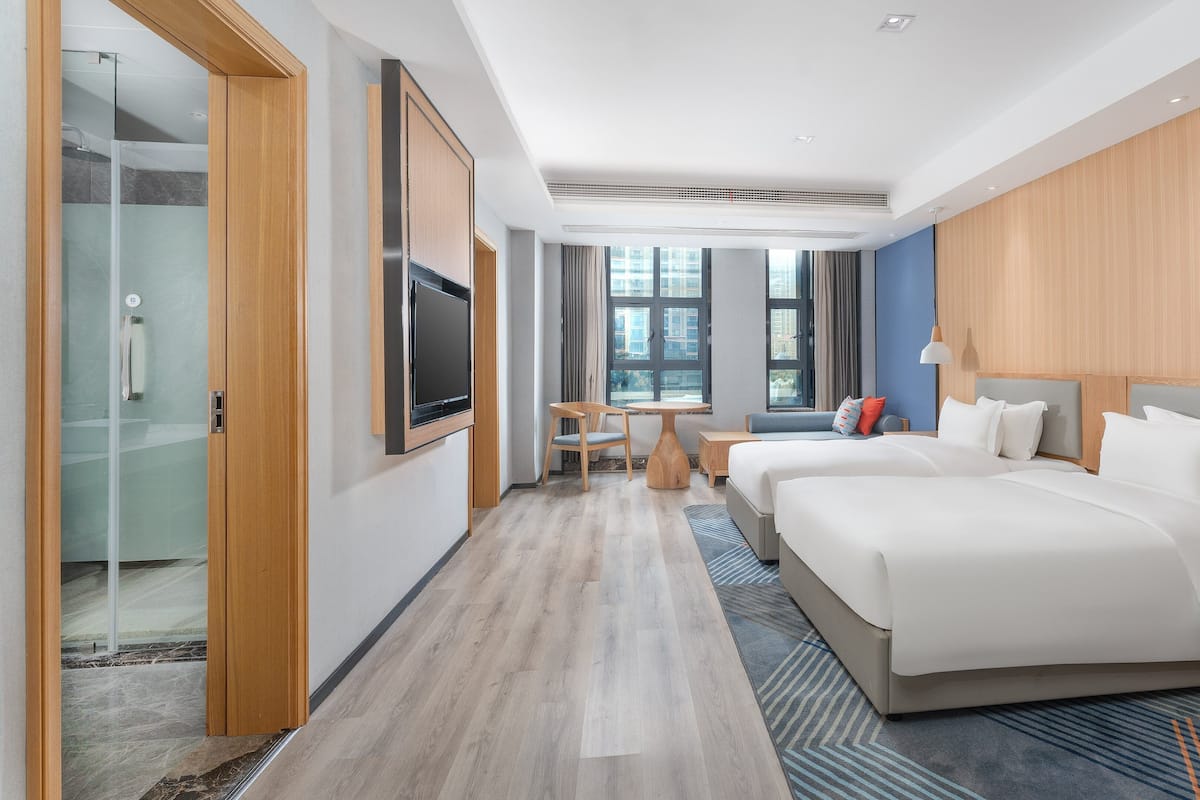 A modern hotel room with a large bed, a desk, and a TV.