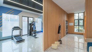 Un gimnasio moderno con equipo de ejercicio, un ventanal grande y un piso limpio y pulido.