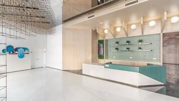 Un hall d’entrée spacieux, doté d’un comptoir d’accueil moderne, d’un luminaire suspendu et d’un panneau décoratif mural.