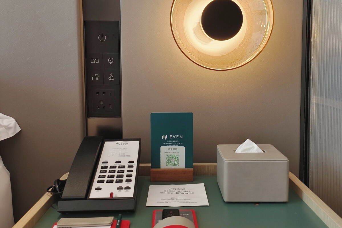 A hotel reception desk with a phone, a QR code sign, a tissue box, and some documents.
