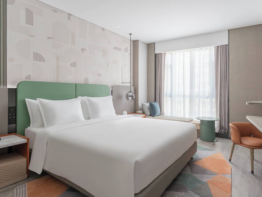 Una habitación de hotel moderna con una cama grande, un escritorio, una silla y un televisor.