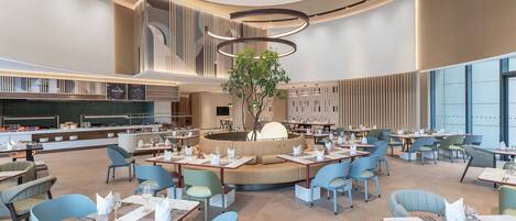 Un comedor amplio con varias mesas y sillas, un área de estar central y un diseño moderno en el techo.