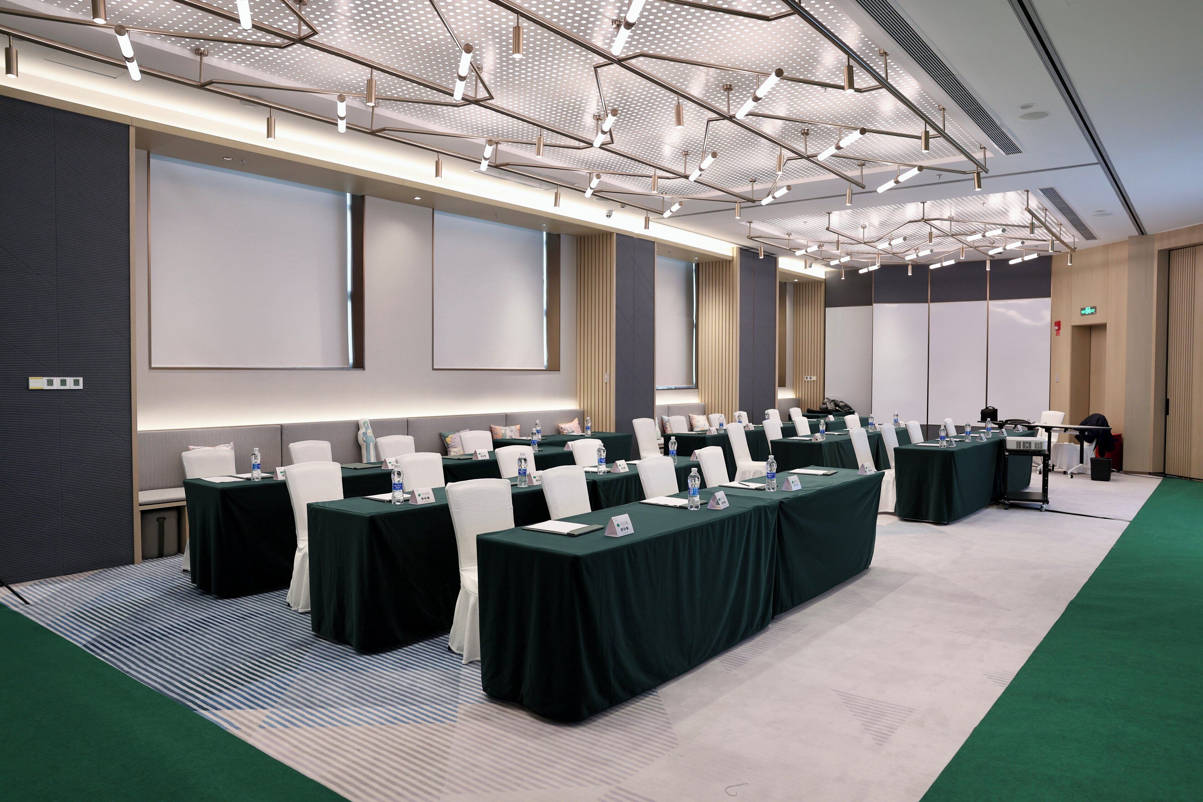 Una sala de conferències amb diverses taules, cadires i una pantalla projectora.