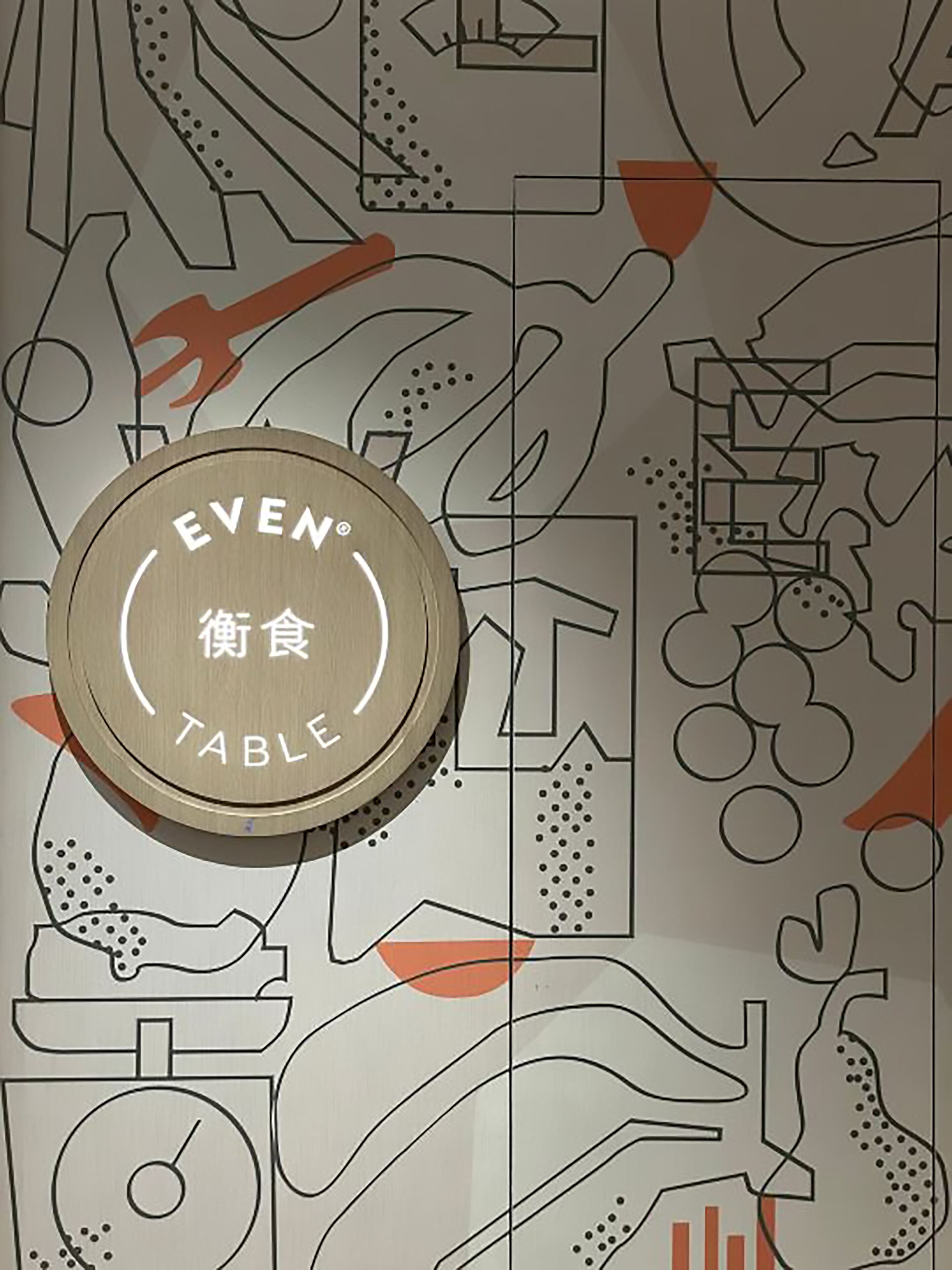 A wall with a geometric pattern and a wooden sign that reads "EVEN TABLE".