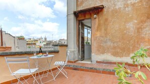 A rooftop terrace with a table and chairs, a potted plant, and a view of the cityscape. - Loft Capocci 37 - Home And More (Roma)
