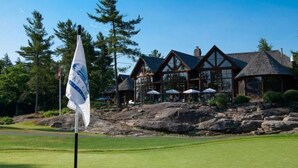 A lodge with a stone facade, large windows, and outdoor seating areas.