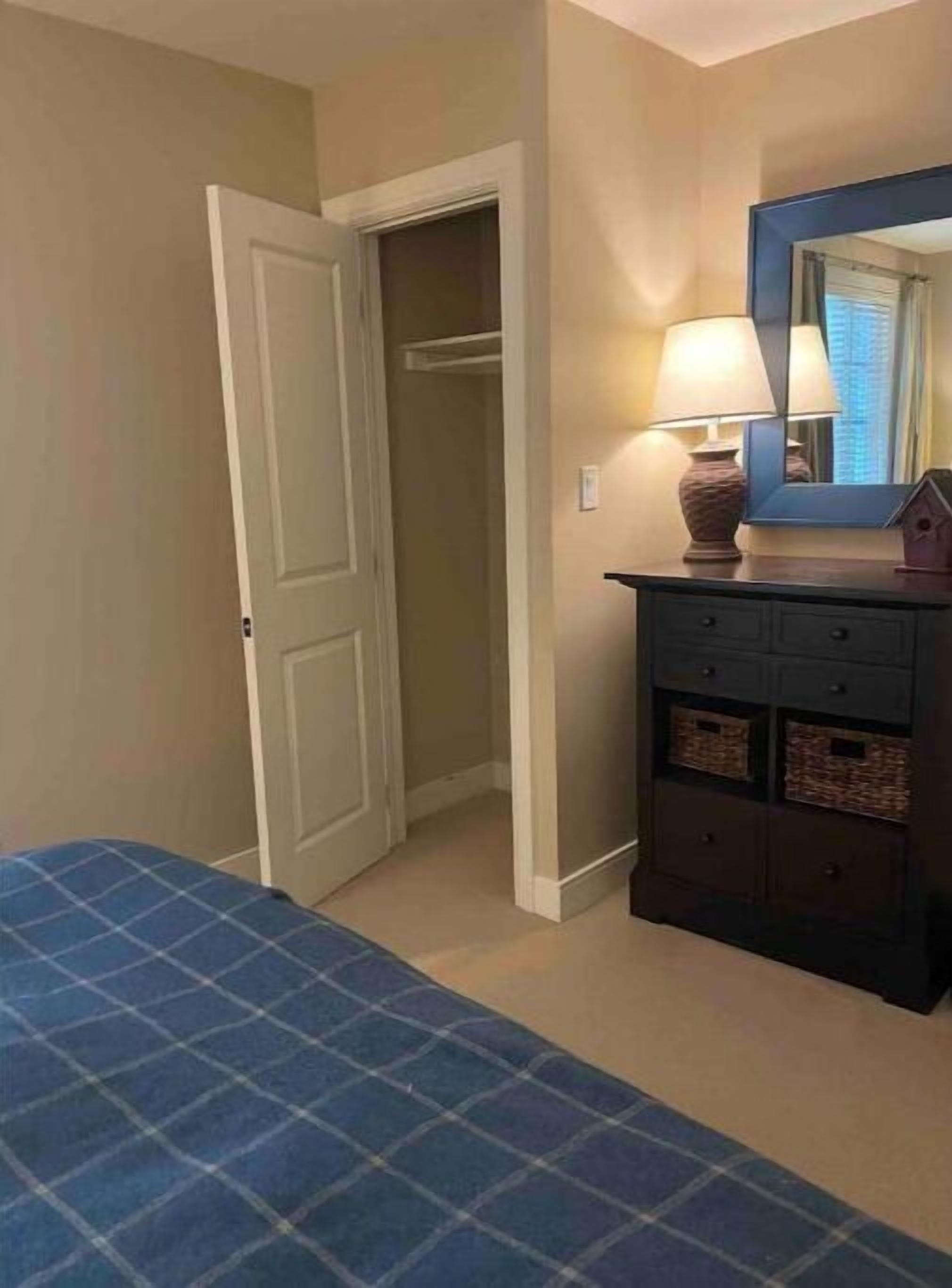 Une chambre à coucher avec un lit, une commode, un miroir et un placard.