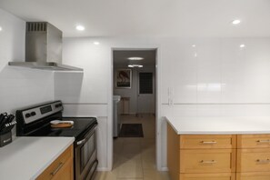 A modern kitchen with white cabinetry, a stove, and a microwave. - Zen 2/2 home 10 min from Siesta Key - Palm Garden (Sarasota)