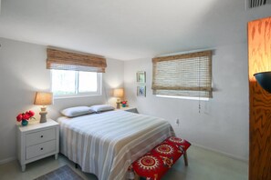 A bedroom with a bed, two bedside tables, a bench, and two windows with blinds. - Zen 2/2 home 10 min from Siesta Key - Palm Garden (Sarasota)