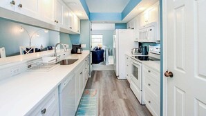 Een moderne keuken met witte kasten, een centraal eiland en uitzicht op een andere kamer.