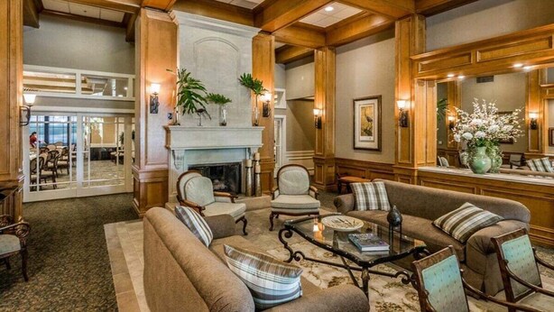 A spacious lobby with a fireplace, comfortable seating, and a large mirror reflecting the room.