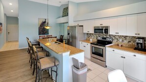 A modern kitchen with a central island, stainless steel appliances, and a dining area with bar stools.