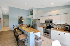 A modern kitchen with a central island, stainless steel appliances, and a dining area with bar stools.