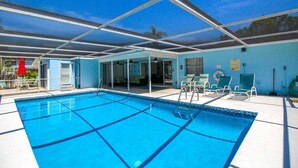 A swimming pool with clear blue water, surrounded by lounge chairs and a covered area with a glass roof. - Stylish 3/2 pool home near Siesta Key - Turtle House (Sarasota)