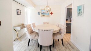 A dining area with a round table and six chairs, a chandelier, and framed artwork on the walls. - Stylish 3/2 pool home near Siesta Key - Turtle House (Sarasota)