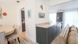 A modern kitchen with dark cabinets, a central island, and a seating area with a sofa. - Stylish 3/2 pool home near Siesta Key - Turtle House (Sarasota)