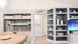 A modern living room with a dining area, built-in shelving, and a television. - Elegant 3 BR/2 BA Private Pool Home - Florida Oasis (Palmetto)