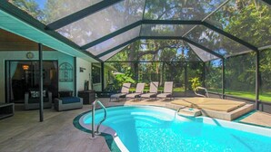 A covered swimming pool with lounge chairs and a view of the surrounding trees. - Elegant 3 BR/2 BA Private Pool Home - Florida Oasis (Palmetto)