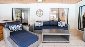 A sunlit patio with wicker furniture, a ceiling fan, and a decorative wall piece. - Elegant 3 BR/2 BA Private Pool Home - Florida Oasis (Palmetto)
