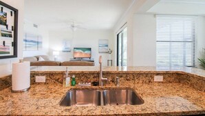 Una cucina moderna con piani di lavoro in granito, lavelli in acciaio inox e una ventola a soffitto.