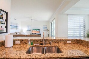 Una cucina moderna con piani di lavoro in granito, lavelli in acciaio inox e una ventola a soffitto.