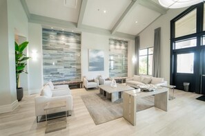 A spacious living room with a large window, a stone wall, and a modern sofa set.