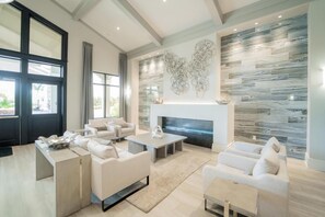 A modern living room with a fireplace, large windows, and a stone wall.