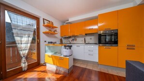 Una cucina con pensili arancioni, un fornello e una finestra con tenda.