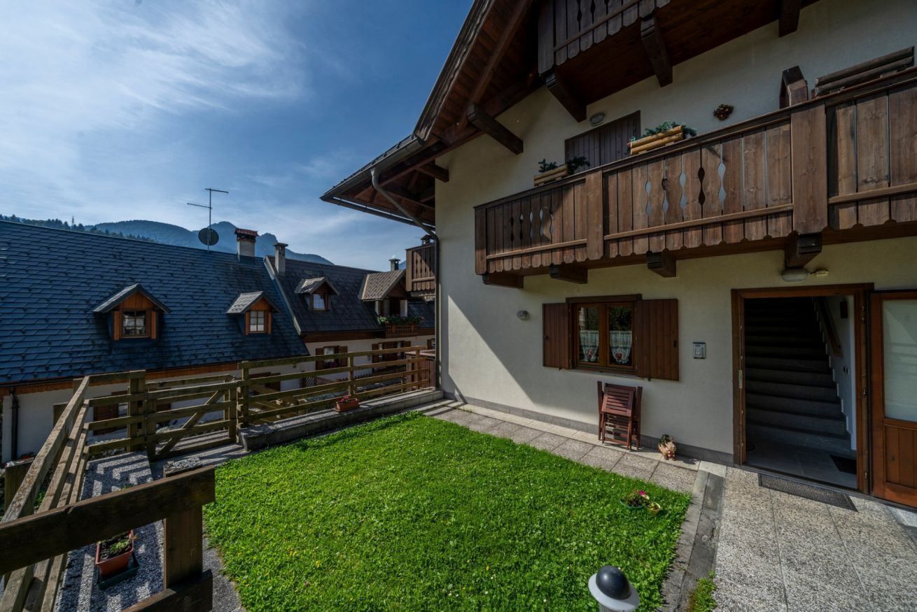 Un chalet traditionnel doté d’un balcon en bois, d’un escalier en pierre et d’une pelouse bien entretenue.