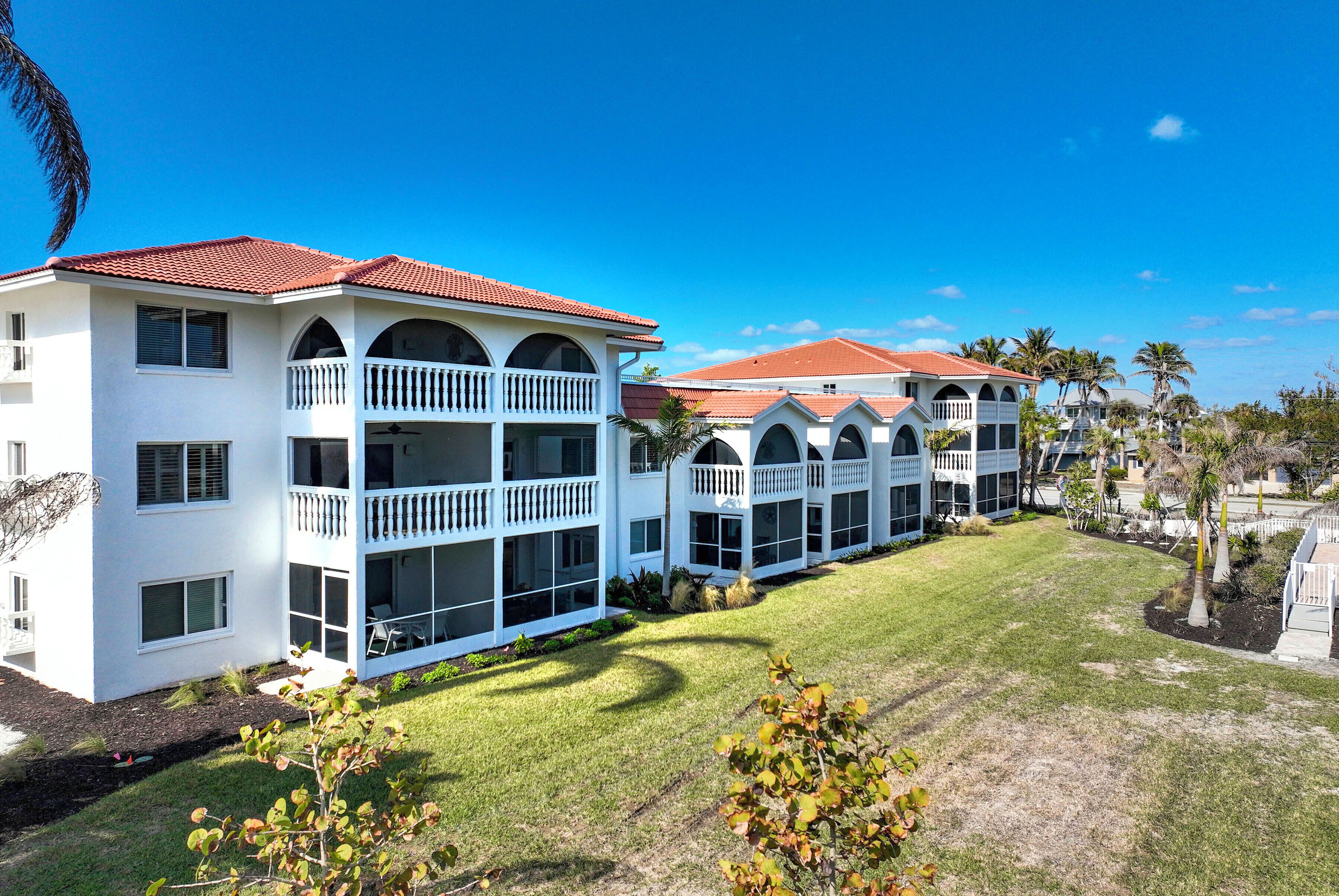A multi-story hotel with balconies, a red-tiled roof, and a well-maintained lawn.