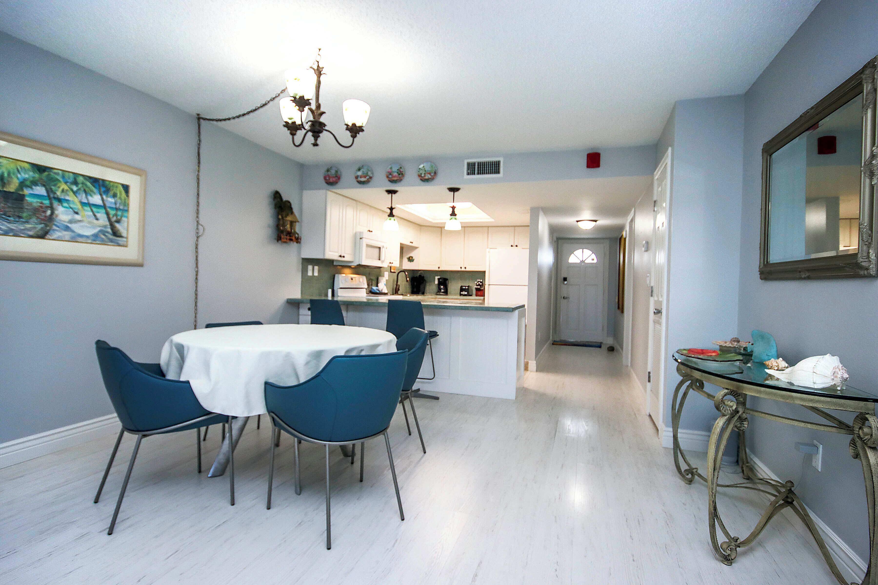 Comedor con una mesa redonda y sillas, cocina al fondo y un pasillo que conduce a otra habitación.