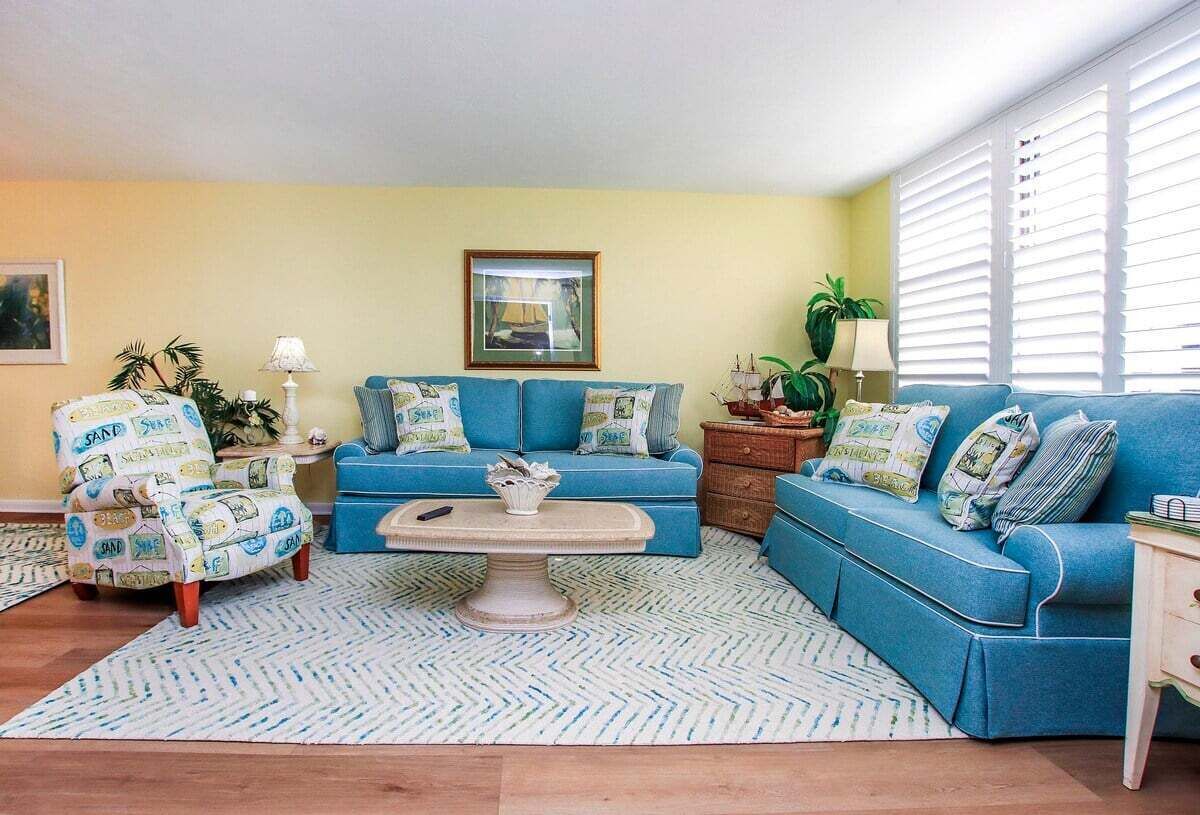A living room with a blue sofa, patterned armchair, and a coffee table.