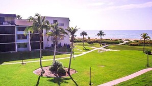 A hotel with a pool area, palm trees, and a view of the ocean.