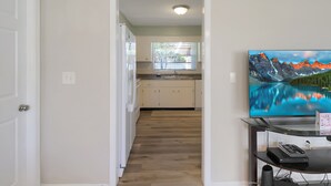 A hallway leading to a kitchen with a large TV mounted on a stand. - Delightful 2 BR / 2 BA Home in West Bradenton - Sans Souci (Bradenton)