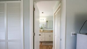 A hallway with a wooden floor, white cabinets, a mirror, and a small plant on the counter. - Spacious 3/2 pool home on Sanibel Island - 10 min walk to beach - Lily Pad (Sanibel)