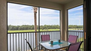 A balcony with a glass table, two chairs, and a view of a lake and greenery. - Cozy 3BR oasis in Lakewood Ranch, perfect for a relaxing getaway - Heavenly Daze (Lakewood Ranch)