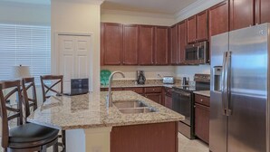 A kitchen with granite countertops, wooden cabinets, stainless steel appliances, and a dining area with chairs. - Cozy 3BR oasis in Lakewood Ranch, perfect for a relaxing getaway - Heavenly Daze (Lakewood Ranch)