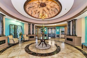 A spacious lobby with a marble floor, a central round table, and tall columns. - Second Floor River Strand Condo Overlooking the Golf Course - Sunny Life (Bradenton)