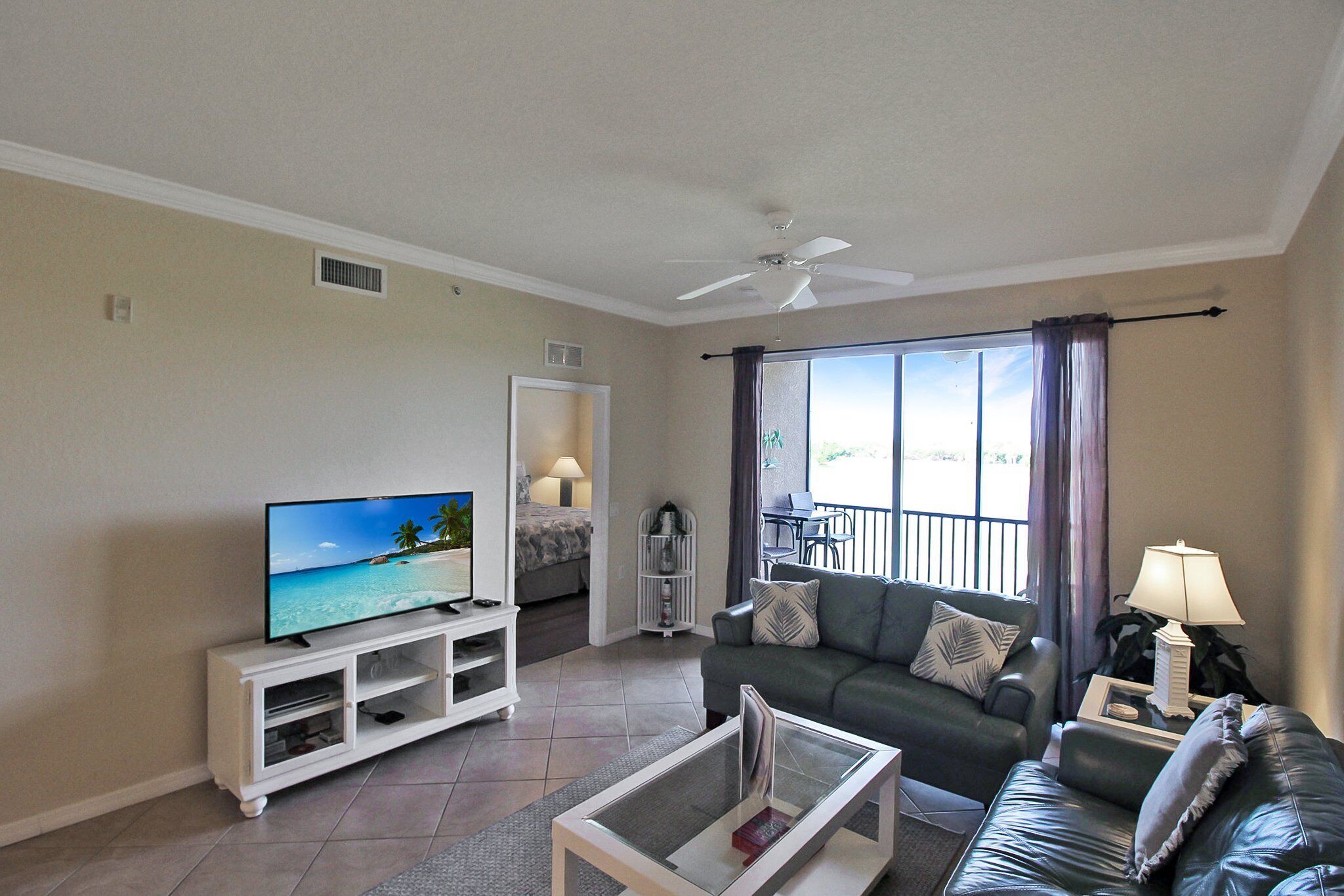 A living room with a TV, a sofa, a coffee table, and a balcony with a view.