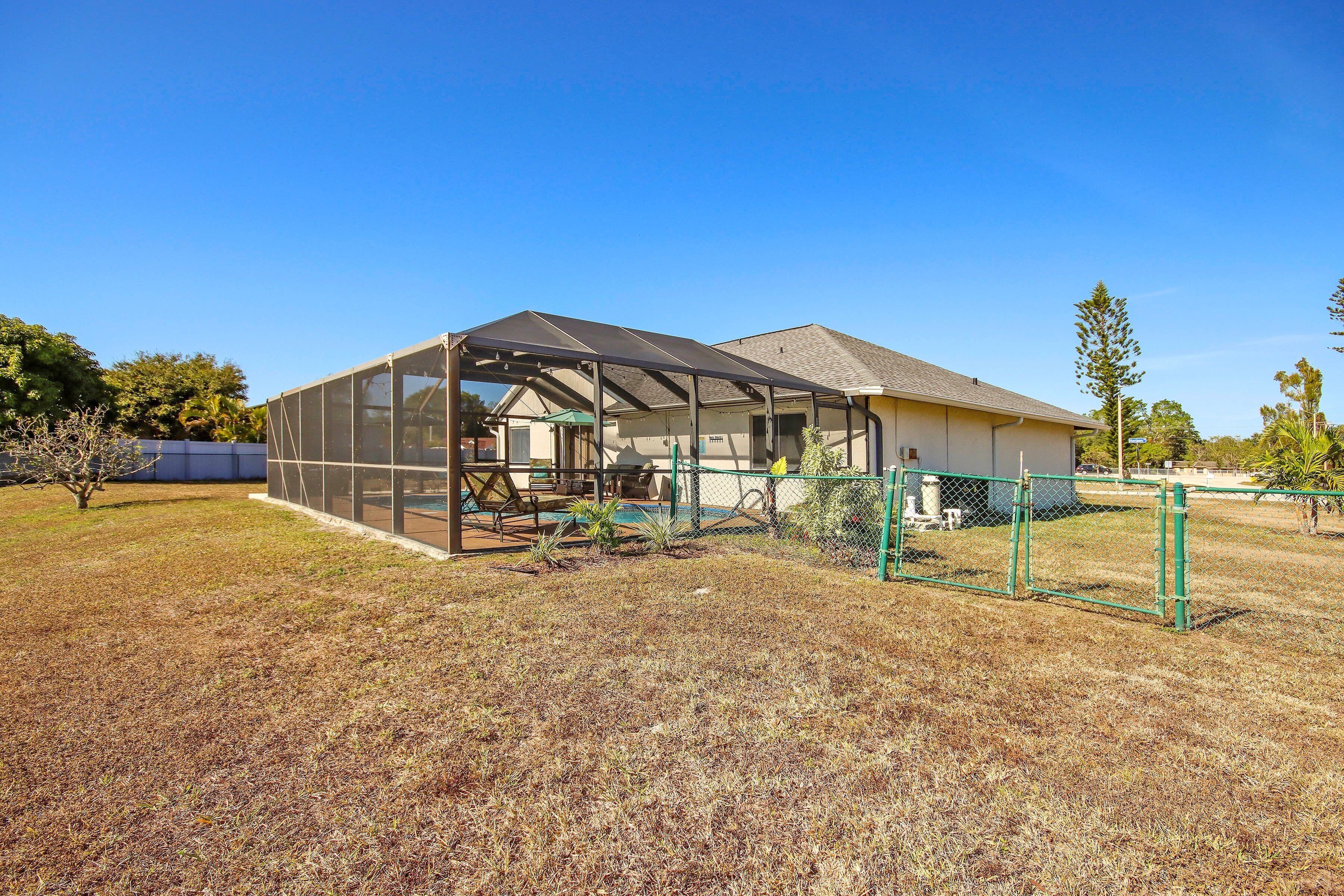 A house with a covered patio area, a fenced yard, and a clear blue sky.