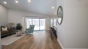 Un salón amplio con un gran ventanal, un sofá, una butaca y una mesita.