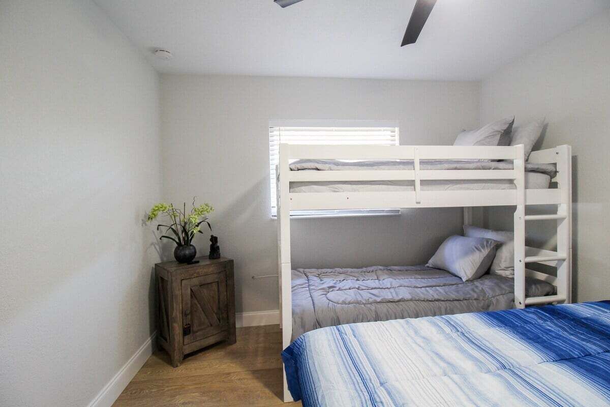Een slaapkamer met een stapelbed, een klein kastje en een bloempot.