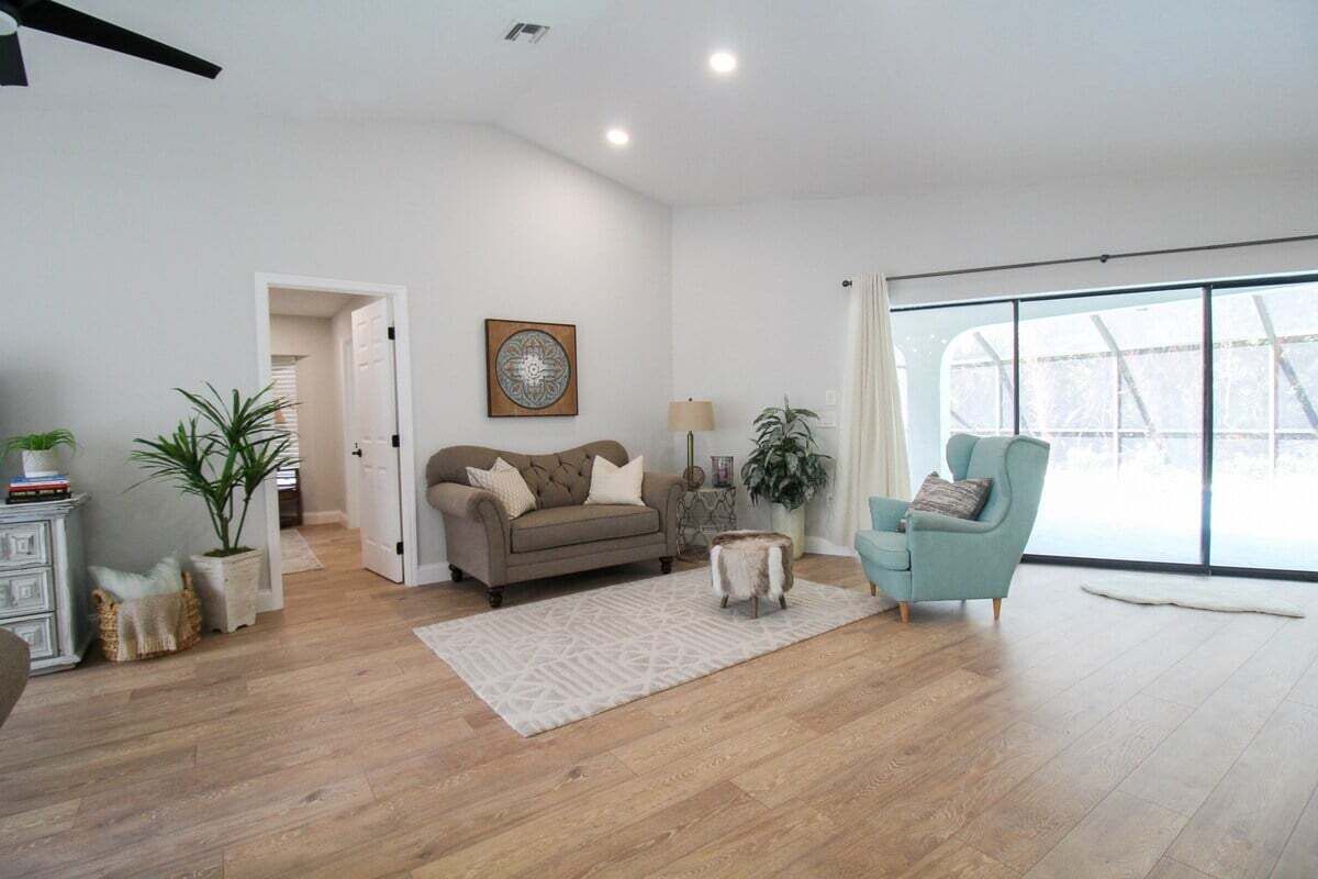 Een ruime woonkamer met een bank, fauteuil en een groot raam.