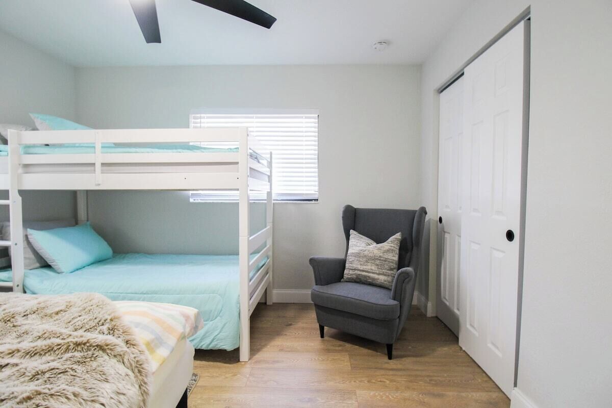 Um quarto com uma cama beliche, uma cadeira e um guarda-roupa.