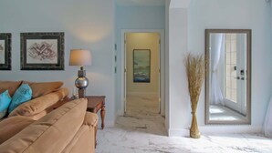 A living room with a sofa, a lamp, a vase, and a door leading to another room. - Gorgeous 3/3 private lakefront pool home - Irynas Dream (Bradenton)